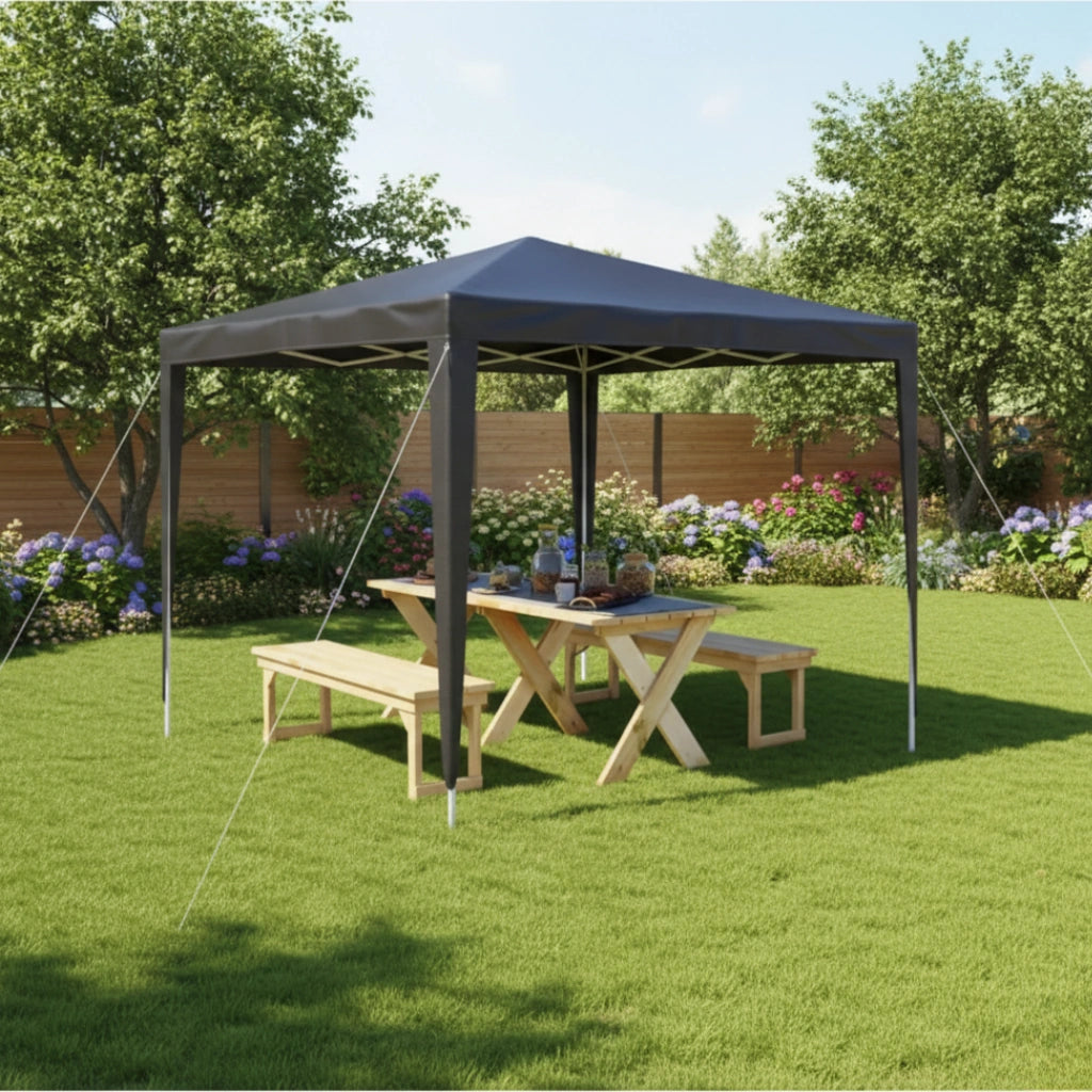 Tente de réception anthracite installée dans un jardin au-dessus d'une table de pique-nique en bois.