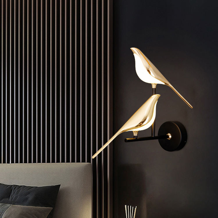 Applique murale LED double tête design oiseau doré et noir, vue de face allumée sur un fond noir 