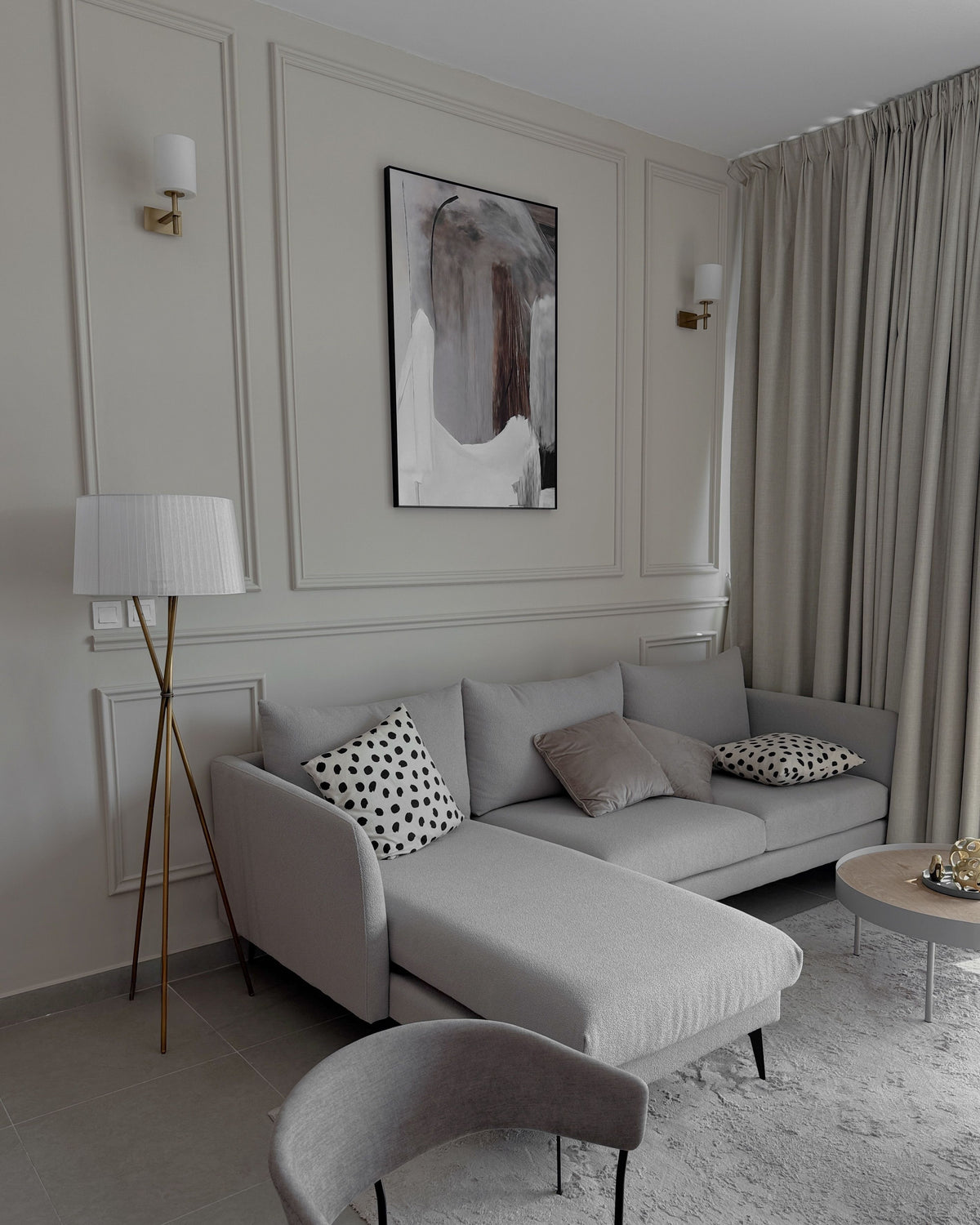 Appliques murales en laiton à abat-jour blanc de part et d'autre d'un cadre dans un salon élégant gris